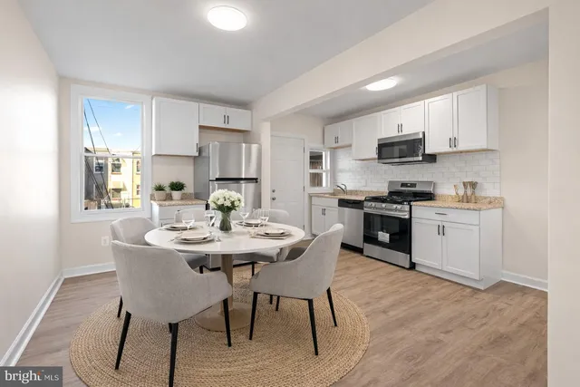 a kitchen with stainless steel appliances kitchen island granite countertop a sink a stove a table and chairs