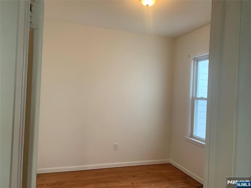 10 Exchange Place, Unit 1 Clifton, NJ 07011 - Photo 11 of 19 a view of an empty room with wooden floor and a window