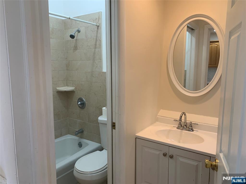 10 Exchange Place, Unit 1 Clifton, NJ 07011 - Photo 15 of 19 a bathroom with a sink a toilet and a mirror