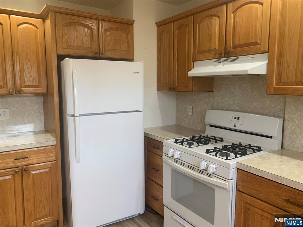 10 Exchange Place, Unit 1 Clifton, NJ 07011 - Photo 8 of 19 a kitchen with stainless steel appliances granite countertop a refrigerator a stove and a sink with cabinets