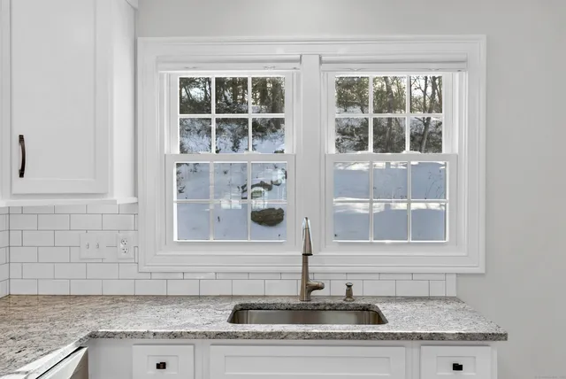 a bathroom with a granite countertop sink and window