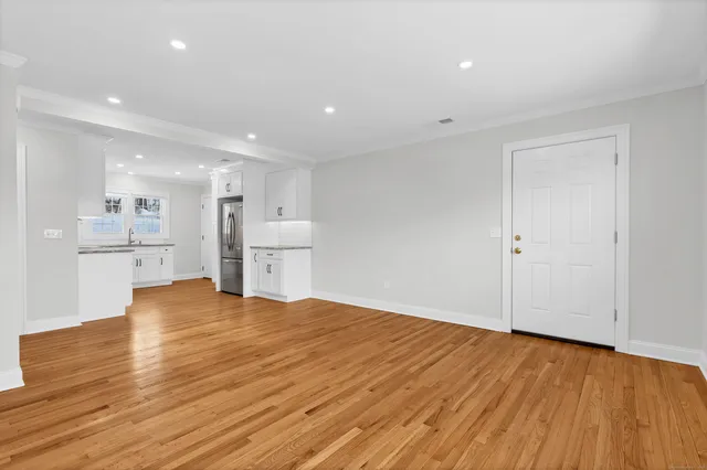 a view of kitchen with empty room and wooden floor