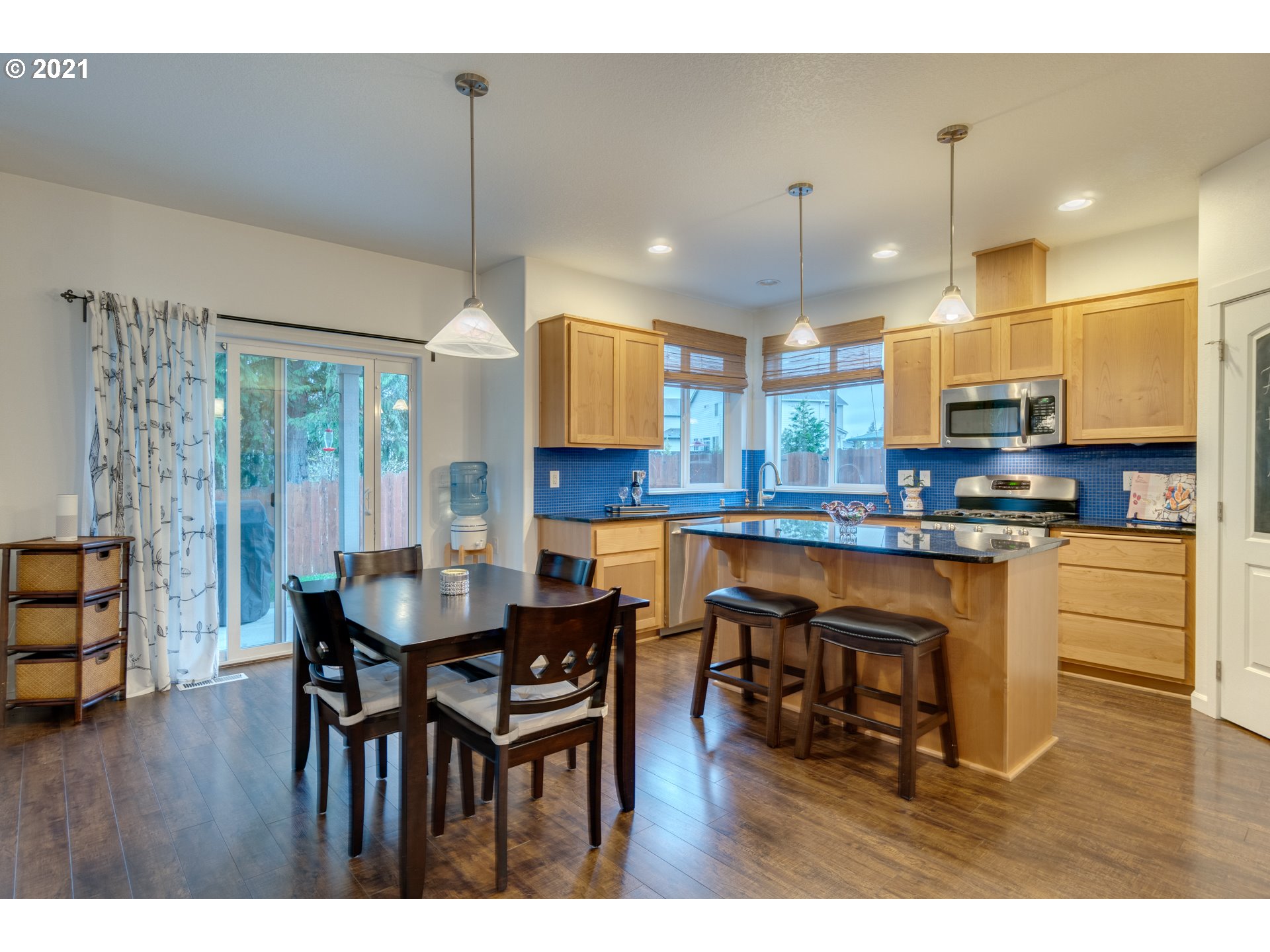 2609 South 18th Court Ridgefield, WA 98642 - Photo 8 of 26 a kitchen with stainless steel appliances granite countertop a stove a refrigerator a kitchen island a dining table and chairs with wooden floor