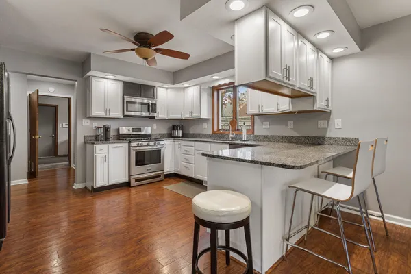 a kitchen with kitchen island granite countertop a sink cabinets and stainless steel appliances