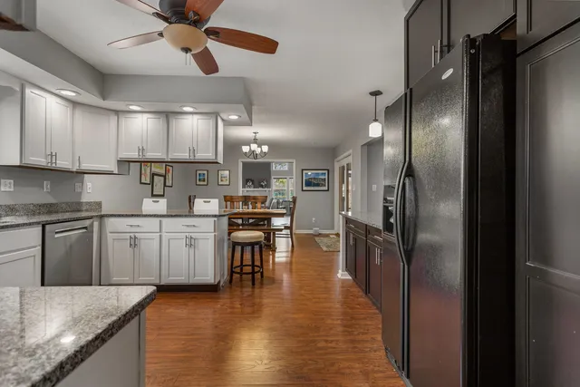 a kitchen with stainless steel appliances granite countertop a refrigerator a sink a stove and white cabinets