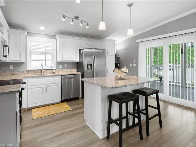 a kitchen with stainless steel appliances granite countertop wooden floor window and cabinets