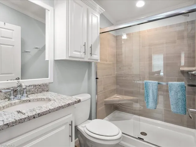 a bathroom with a granite countertop sink a toilet a mirror and shower