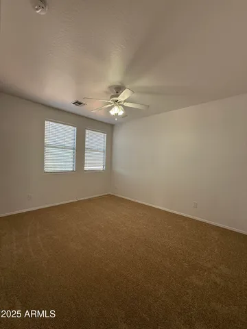 an empty room with a chandelier fan and windows