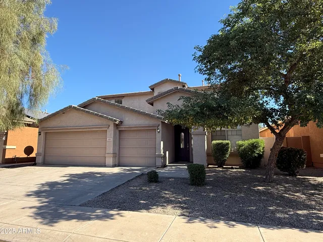 a front view of a house with yard garage and tree