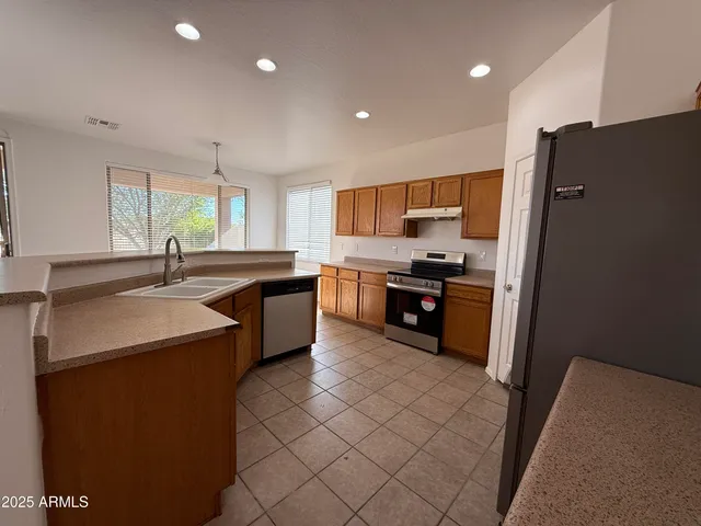 a kitchen with stainless steel appliances a sink a stove a refrigerator a center island and a window