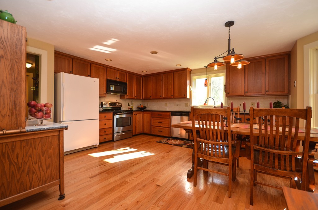 66 Barnett Road Sutton, MA 01590 - Photo 4 of 30 a kitchen with stainless steel appliances granite countertop a refrigerator a stove a sink a dining table and chairs with wooden floor