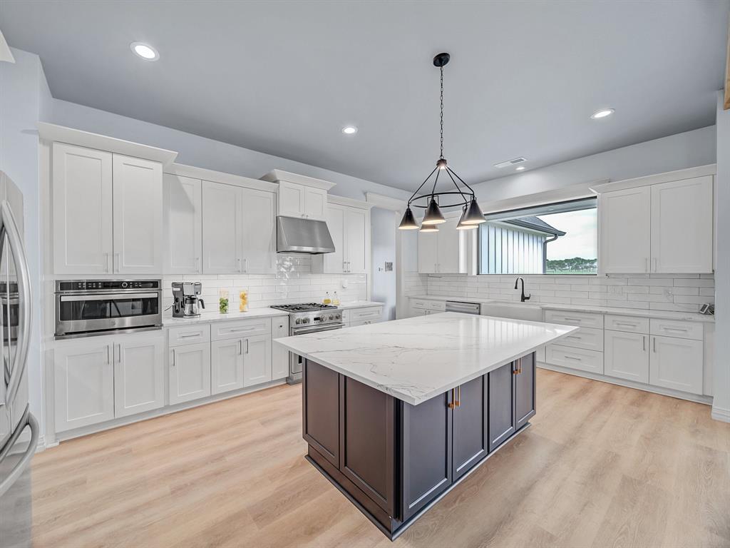a kitchen with kitchen island a sink wooden floor and white appliances