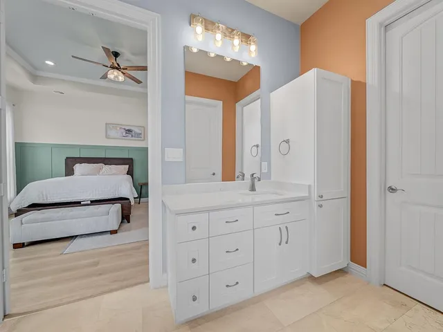 a spacious bedroom with a double vanity sink and a mirror