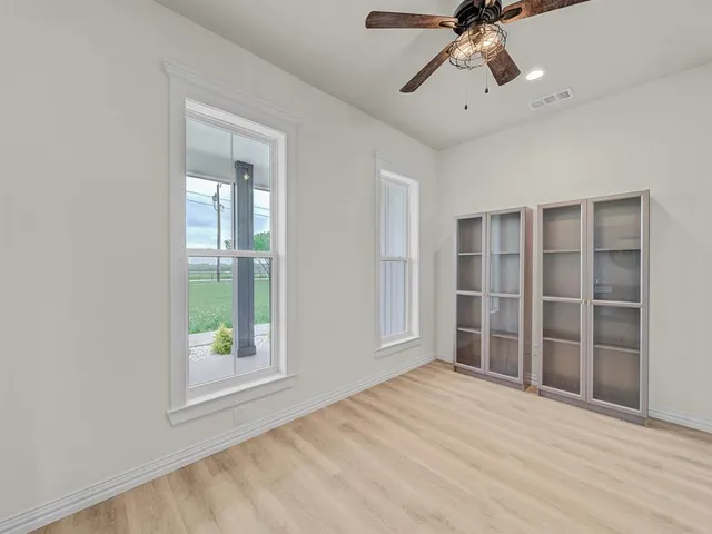 a view of empty room with wooden floor and fan