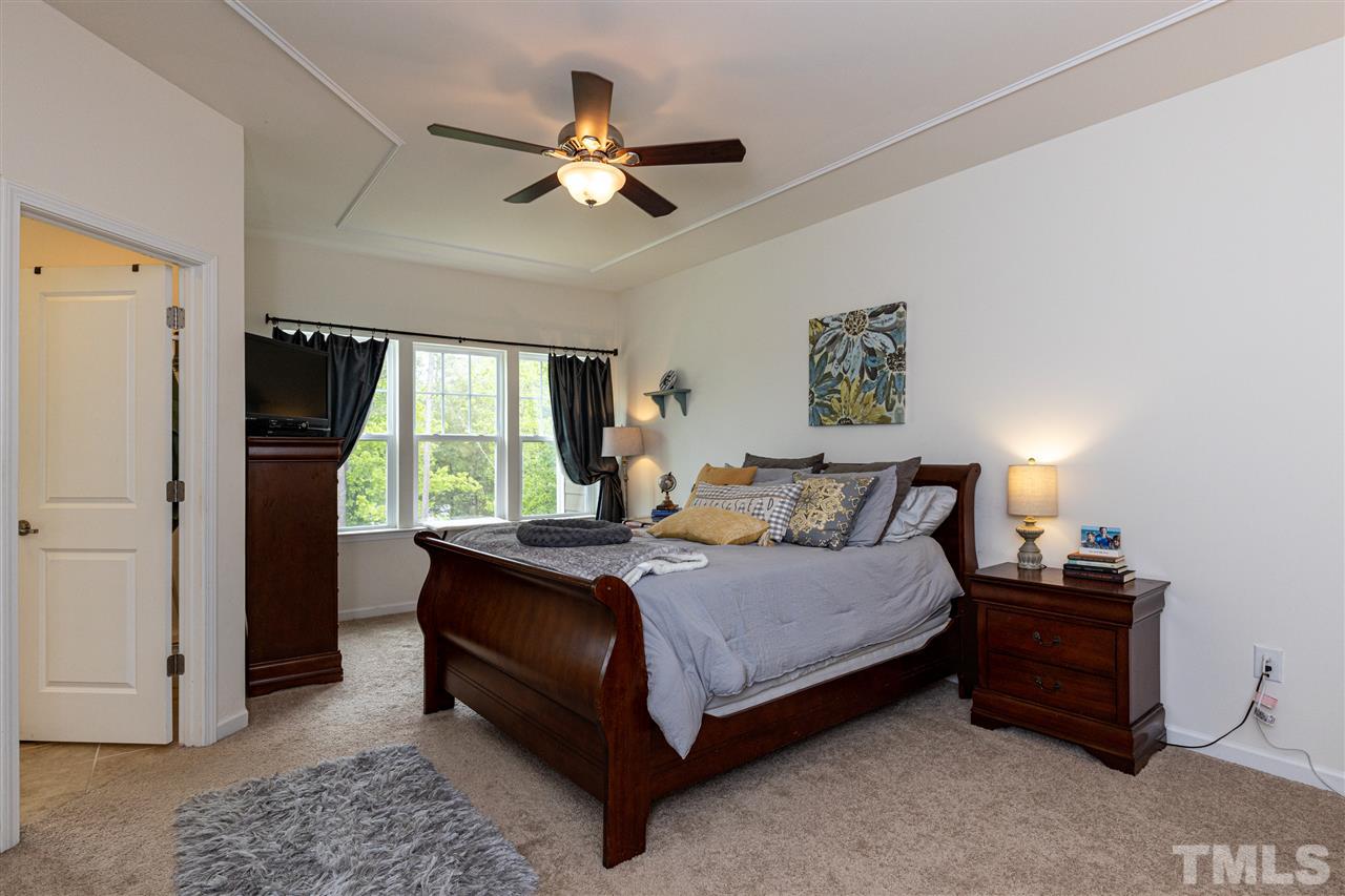 724 Edgewater Ridge Court Apex, NC 27523 - Photo 13 of 30 a bedroom with a bed and a chandelier