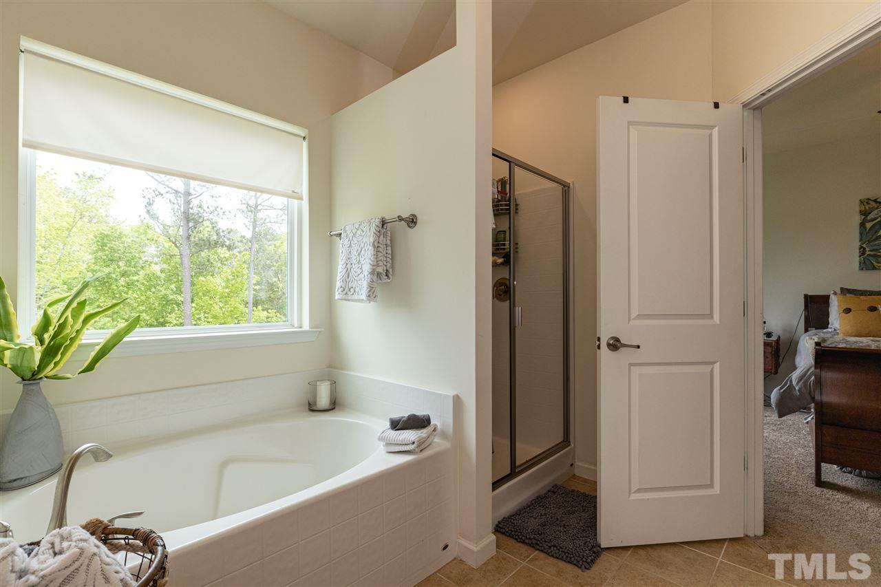 724 Edgewater Ridge Court Apex, NC 27523 - Photo 16 of 30 a bathroom with a bathtub a window and a shower