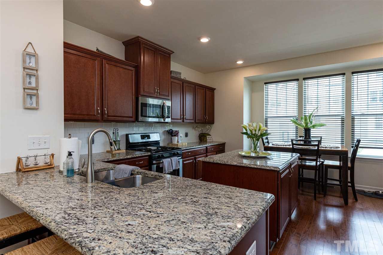 724 Edgewater Ridge Court Apex, NC 27523 - Photo 3 of 30 a kitchen with stainless steel appliances granite countertop wooden cabinets a stove top oven a sink and dishwasher