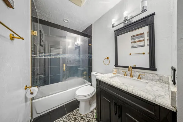 a bathroom with a granite countertop sink a toilet a mirror and bathtub