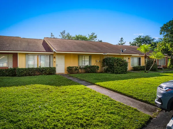 a view of a white house next to a yard with big trees