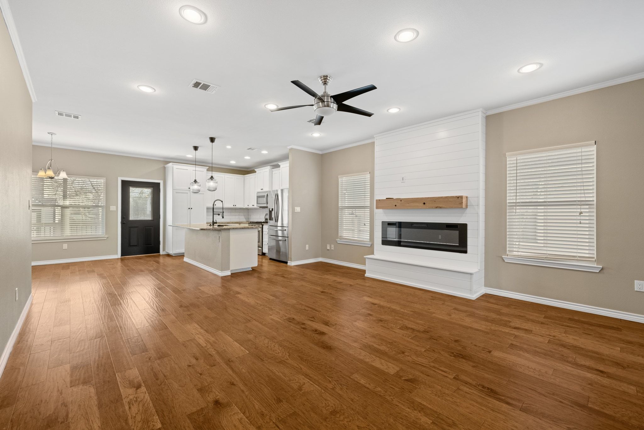 609 A West 7th Street Taylor, TX 76574 - Photo 6 of 35 an empty room with wooden floor a ceiling fan and kitchen view