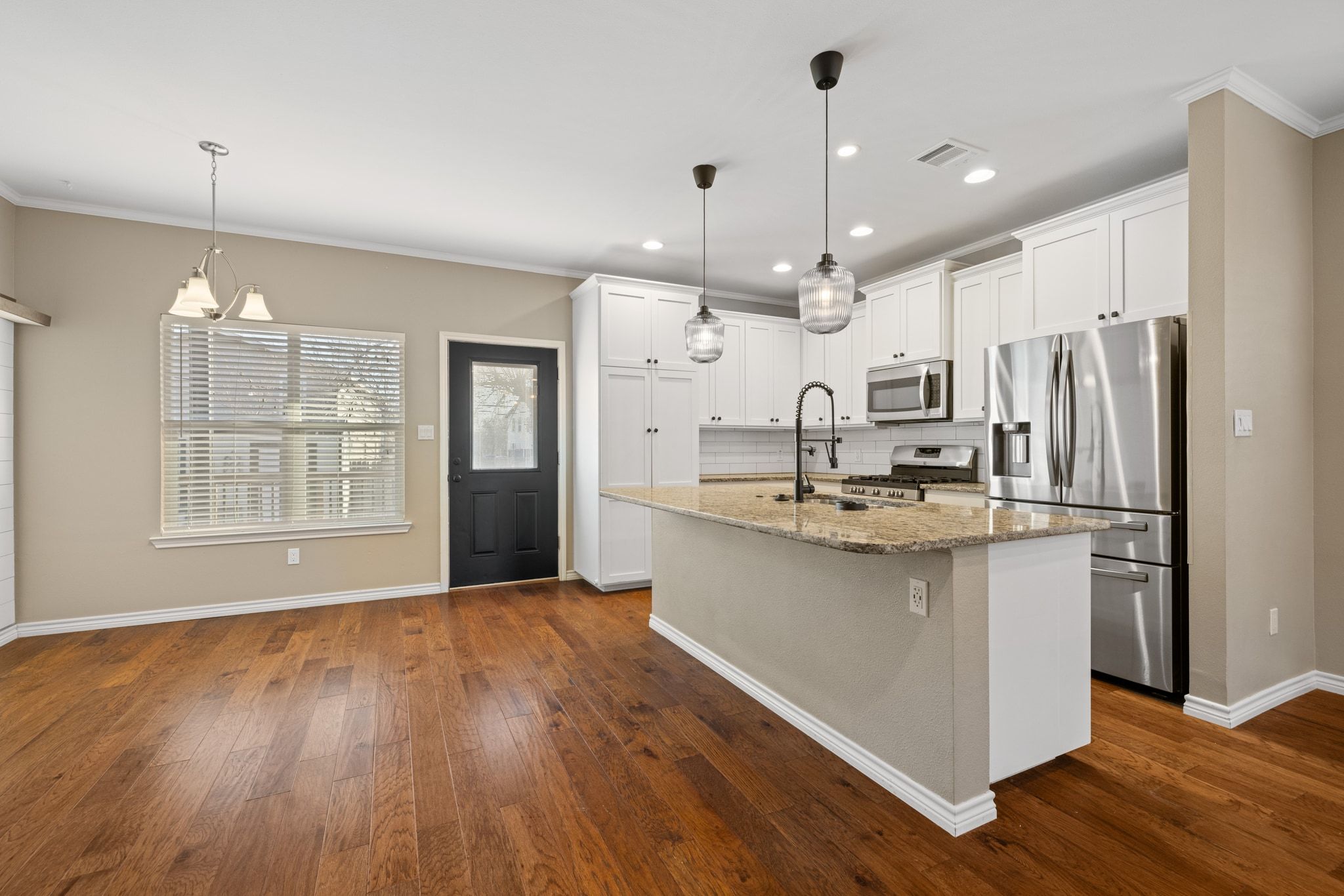 609 A West 7th Street Taylor, TX 76574 - Photo 9 of 35 a large kitchen with granite countertop a large counter top space stainless steel appliances a window and a chandelier