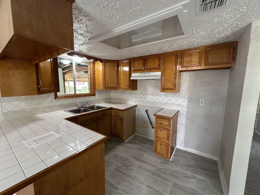 6523 Hanley Lane Houston, TX 77016 - Photo 3 of 17 a kitchen with granite countertop a sink a stove and wooden cabinets