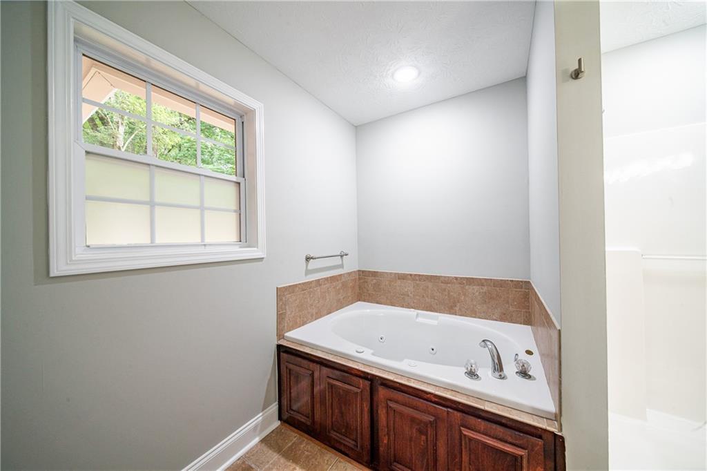 1927 Lee Road Salem, AL 36874 - Photo 32 of 45 Bathroom featuring a tub with jets, a textured ceiling, and light tile patterned flooring