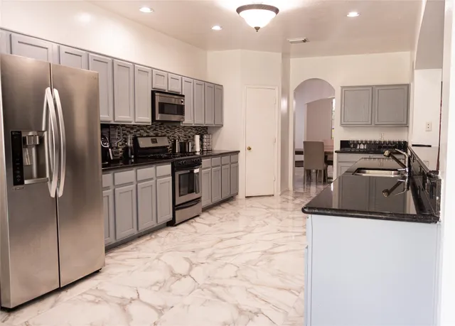 a kitchen with stainless steel appliances granite countertop a refrigerator sink and microwave