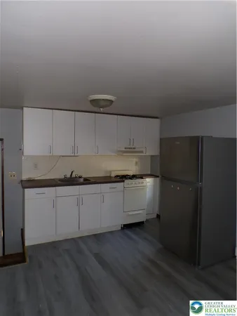 a kitchen with granite countertop white cabinets and refrigerator
