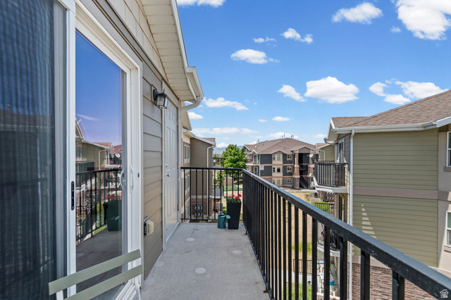 8248 South Resaca Drive, Unit J10 Sandy, UT 84070 - Photo 24 of 40 Private concrete balcony featuring a black metal railing, sliding glass door, and exterior sconce lighting