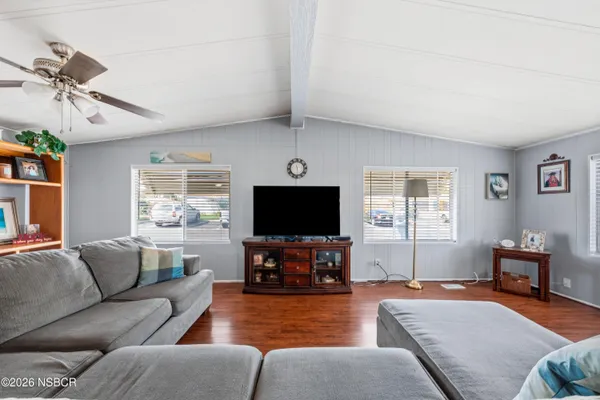 a living room with furniture a wooden floor and next to dining room