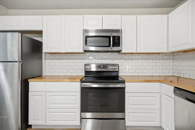 a kitchen with white cabinets and stainless steel appliances