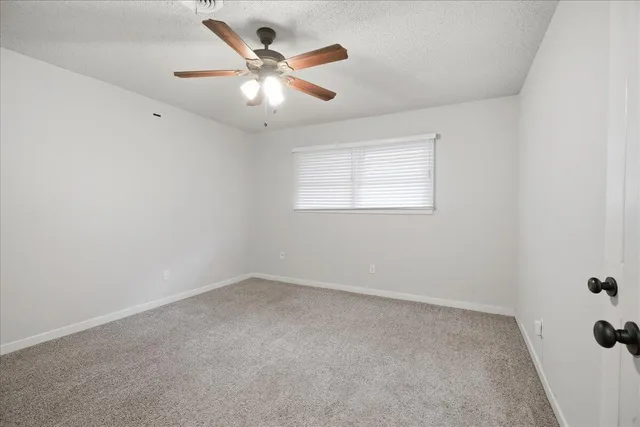 an empty room with a window and a fan