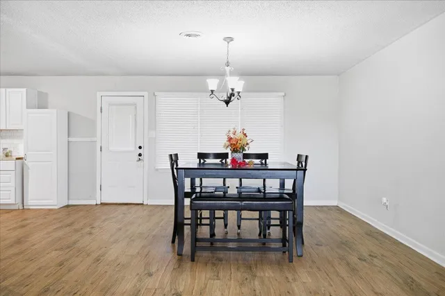 a view of a dining room with furniture a chandelier and wooden floor