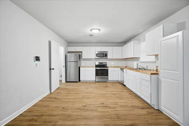 a large kitchen with white cabinets and stainless steel appliances