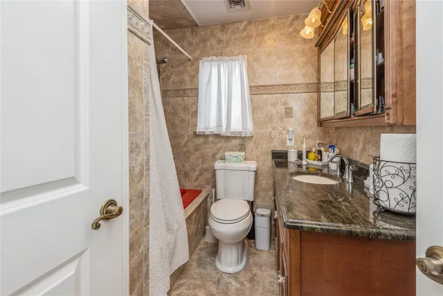 a bathroom with a granite countertop sink a toilet and a mirror