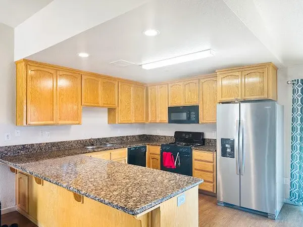 a kitchen with refrigerator granite countertop sink and dishwasher a refrigerator with wooden cabinets