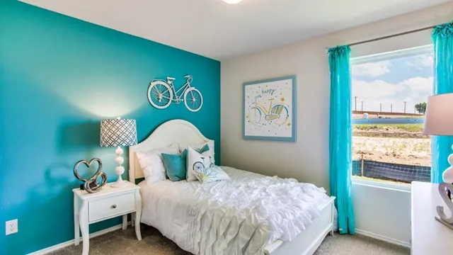 a bedroom with a bed and a lamp on dresser next to a window