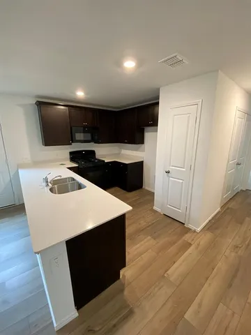 a kitchen with kitchen island a sink dishwasher a stove and a refrigerator with wooden floor