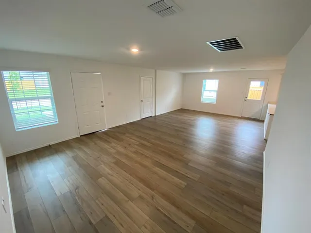 an empty room with wooden floor and windows