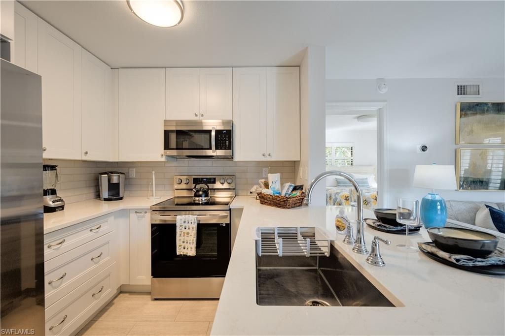655 8th Avenue South, Unit 3 Naples, FL 34102 - Photo 2 of 48 a kitchen with a stove a sink and a white cabinets