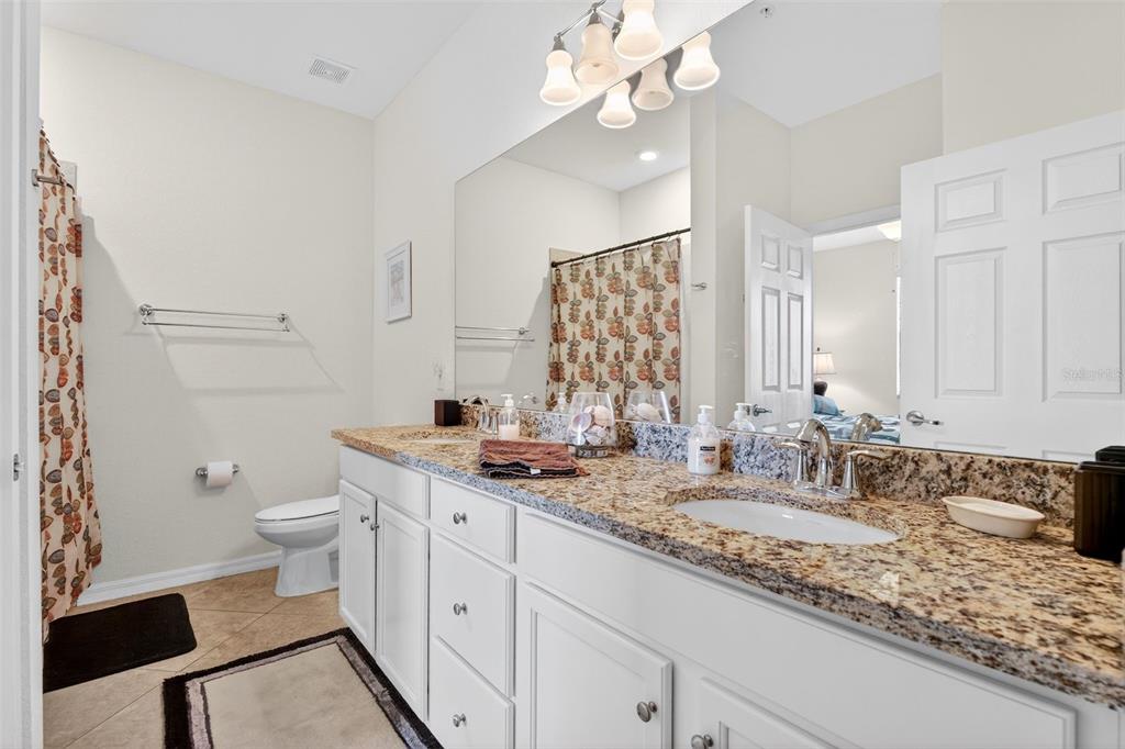16904 Vardon Terrace, Unit 301 Lakewood Ranch, FL 34211 - Photo 18 of 53 a bathroom with a granite countertop double vanity sink a mirror and a toilet