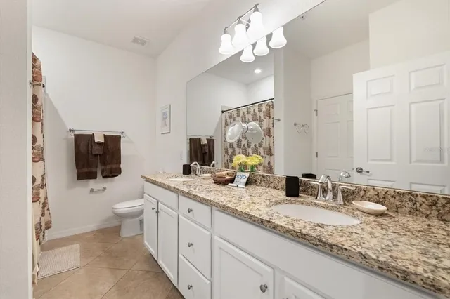 a bathroom with a granite countertop sink a toilet a mirror and shower