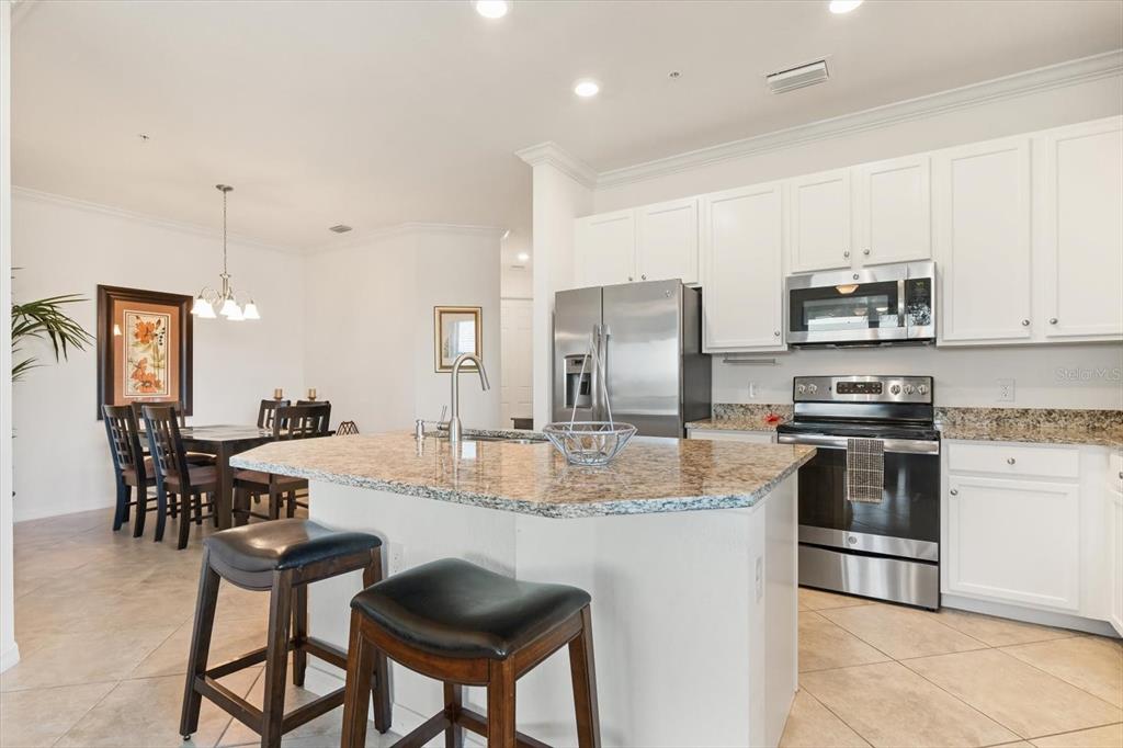 16904 Vardon Terrace, Unit 301 Lakewood Ranch, FL 34211 - Photo 9 of 28 a kitchen with kitchen island granite countertop a stove and cabinets