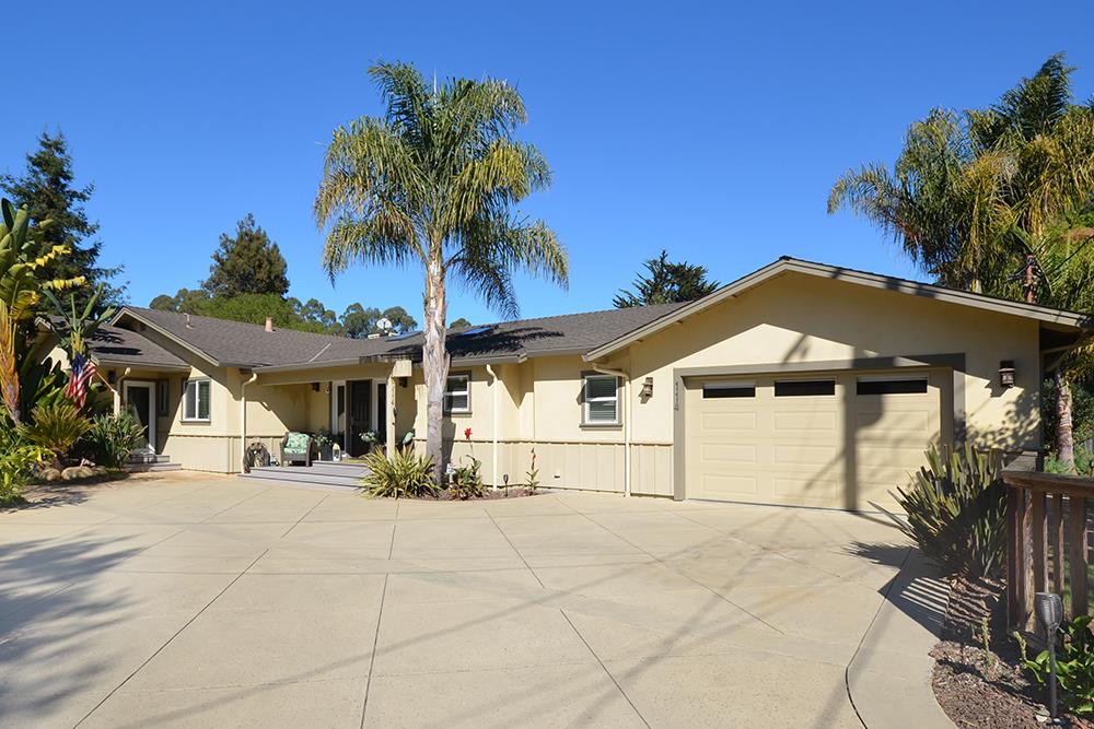 a view of a white house with a yard and potted plants