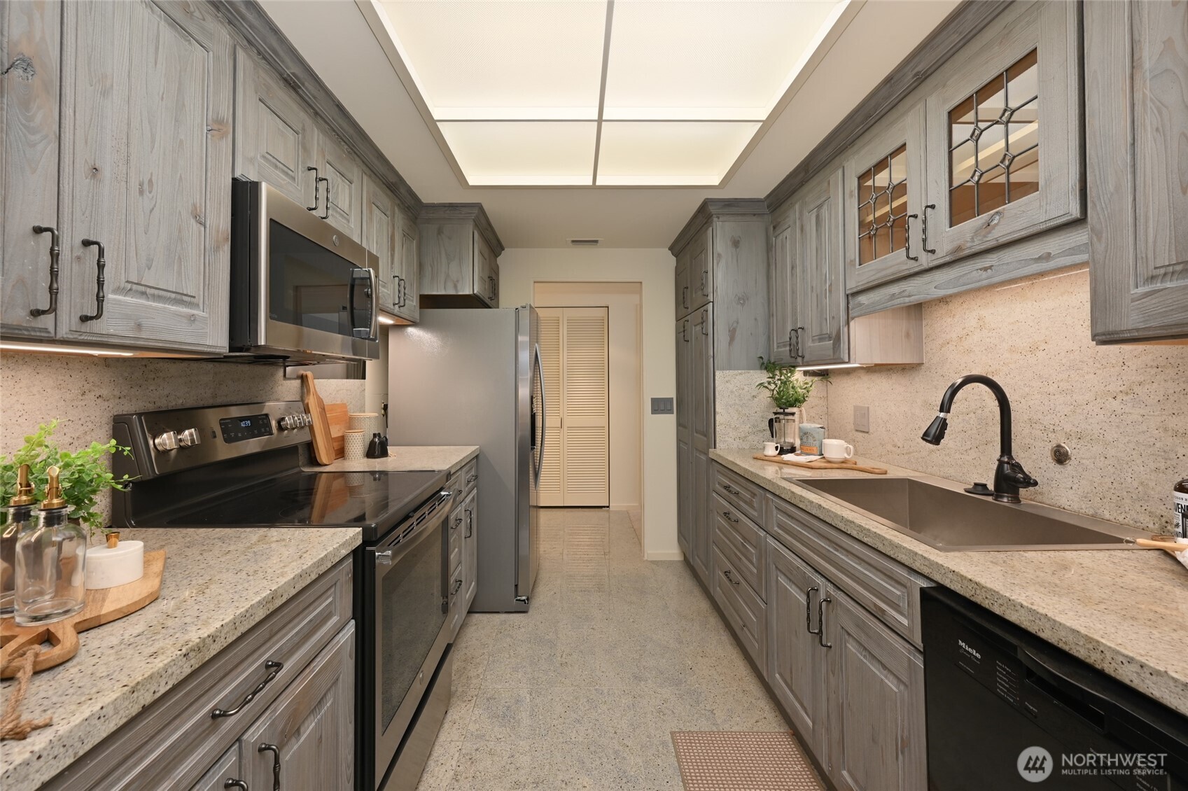 1301 Spring Street, Unit 6D Seattle, WA 98104 - Photo 8 of 29 a kitchen with stainless steel appliances granite countertop a sink a stove and a refrigerator