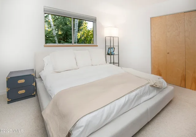 a large bed sitting in a bedroom next to a window