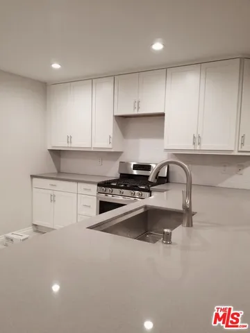 a kitchen with stainless steel appliances granite countertop a sink stove and white cabinets
