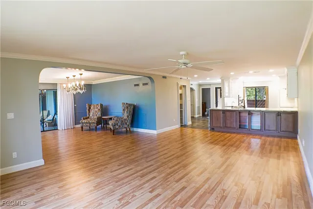 a view of a living room and kitchen with furniture wooden floor and chandelier
