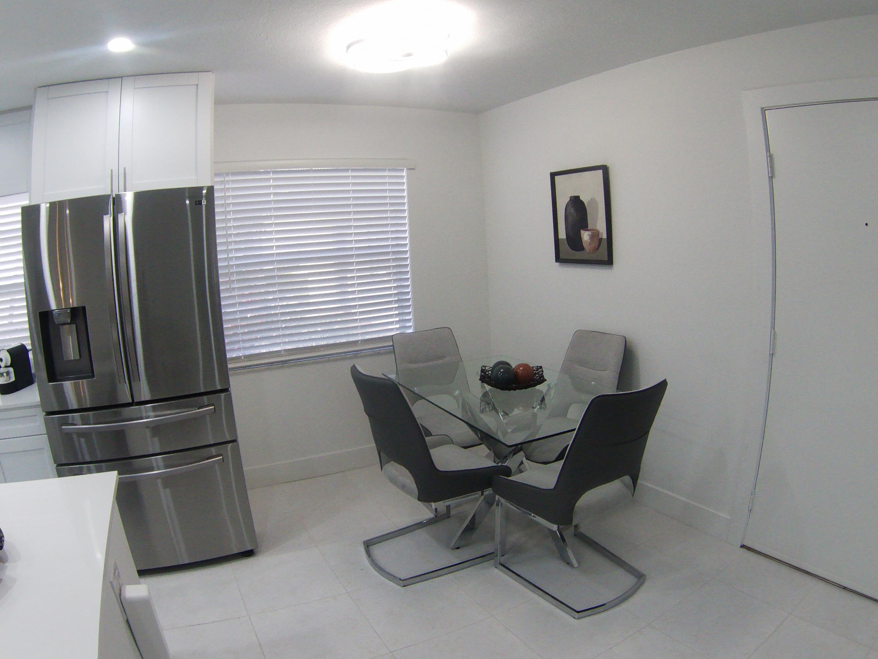541 Normandy Lane Delray Beach, FL 33484 - Photo 9 of 23 a kitchen with stainless steel appliances wooden floor and chairs